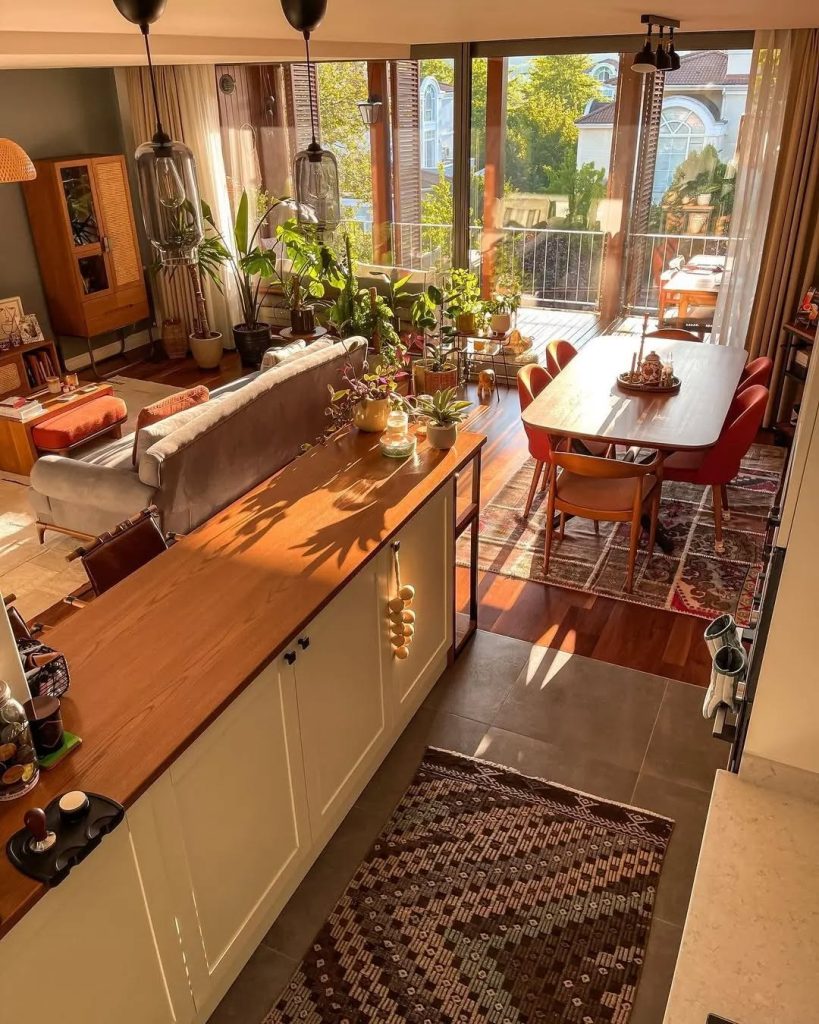 Sunlit boho kitchen with mid-century furniture and lush greenery.
