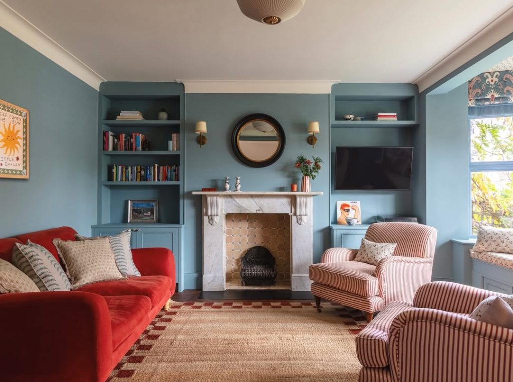 Warm leather sofa contrasts with deep blue walls for a cozy, modern living space