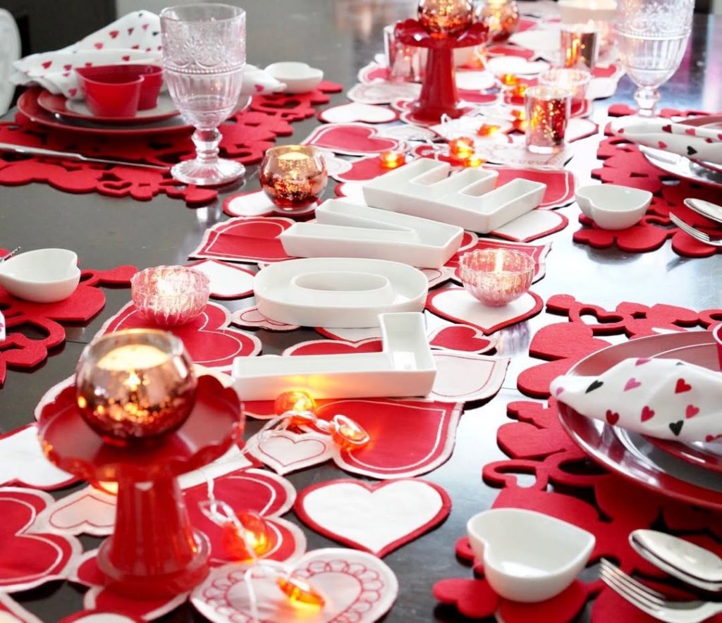 Playful red and white romantic tablescape with glowing candles and heart decor.
