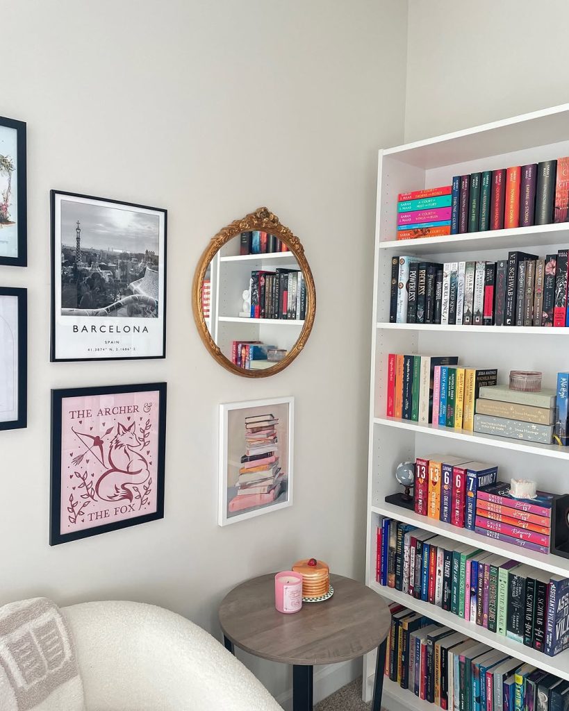  A white chair beside a bookshelf in a room featuring a large mirror on the wall, creating a spacious atmosphere.