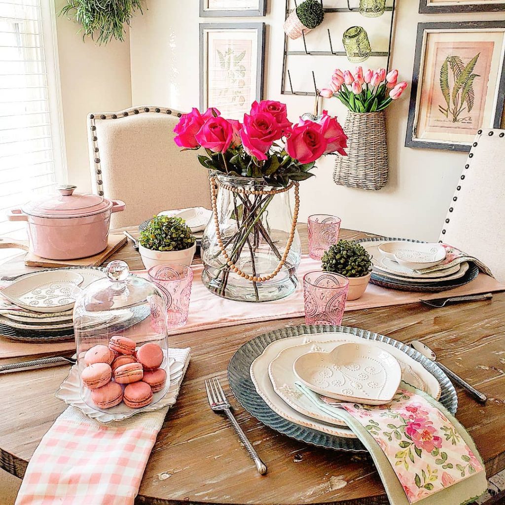 Rustic romantic table setting with pink glassware, roses, and macarons.
