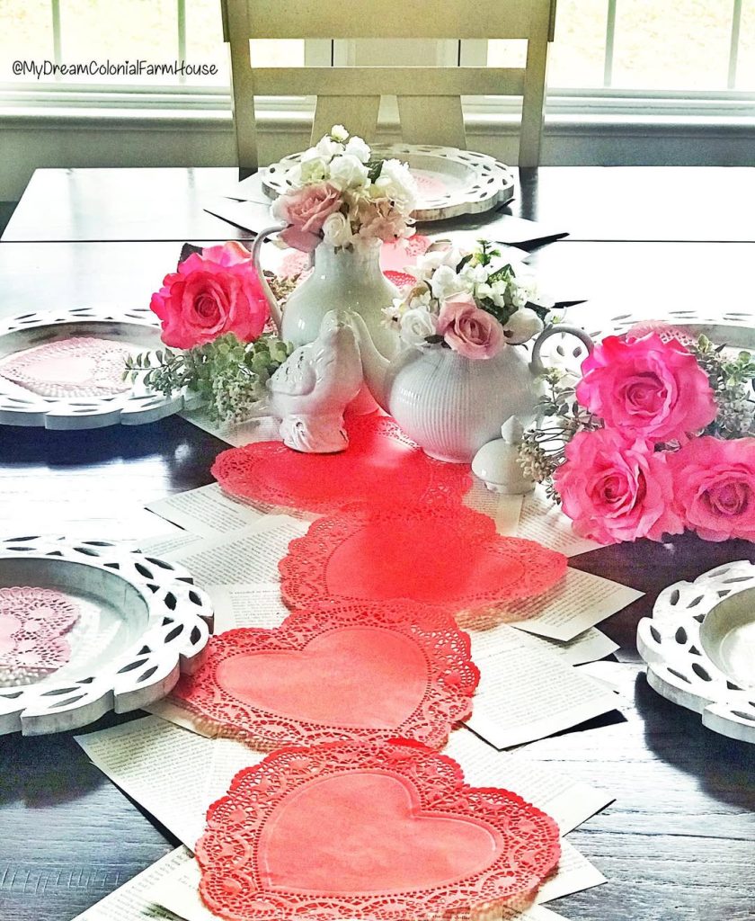 Vintage-inspired romantic table with lacy heart doilies and pink roses.
