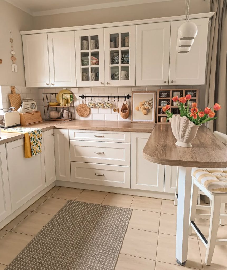 Minimalist boho kitchen with elegant white cabinets and fresh flowers.
