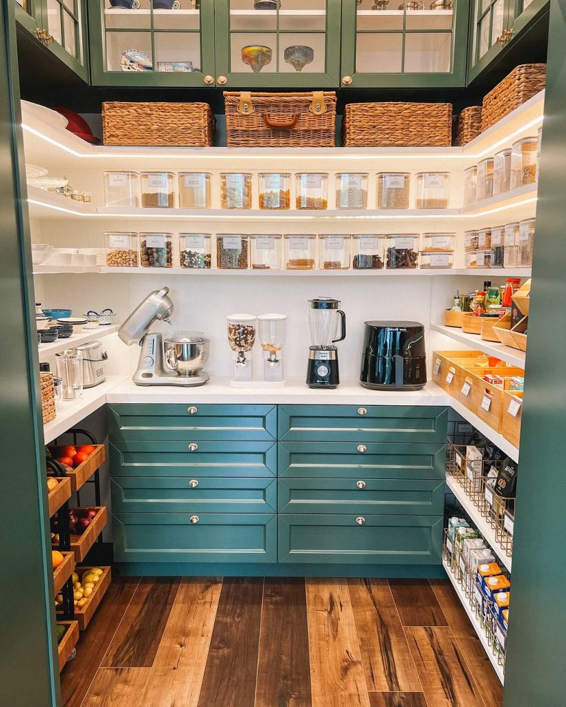 Bold green pantry with built-in produce drawers and glass storage jars.
