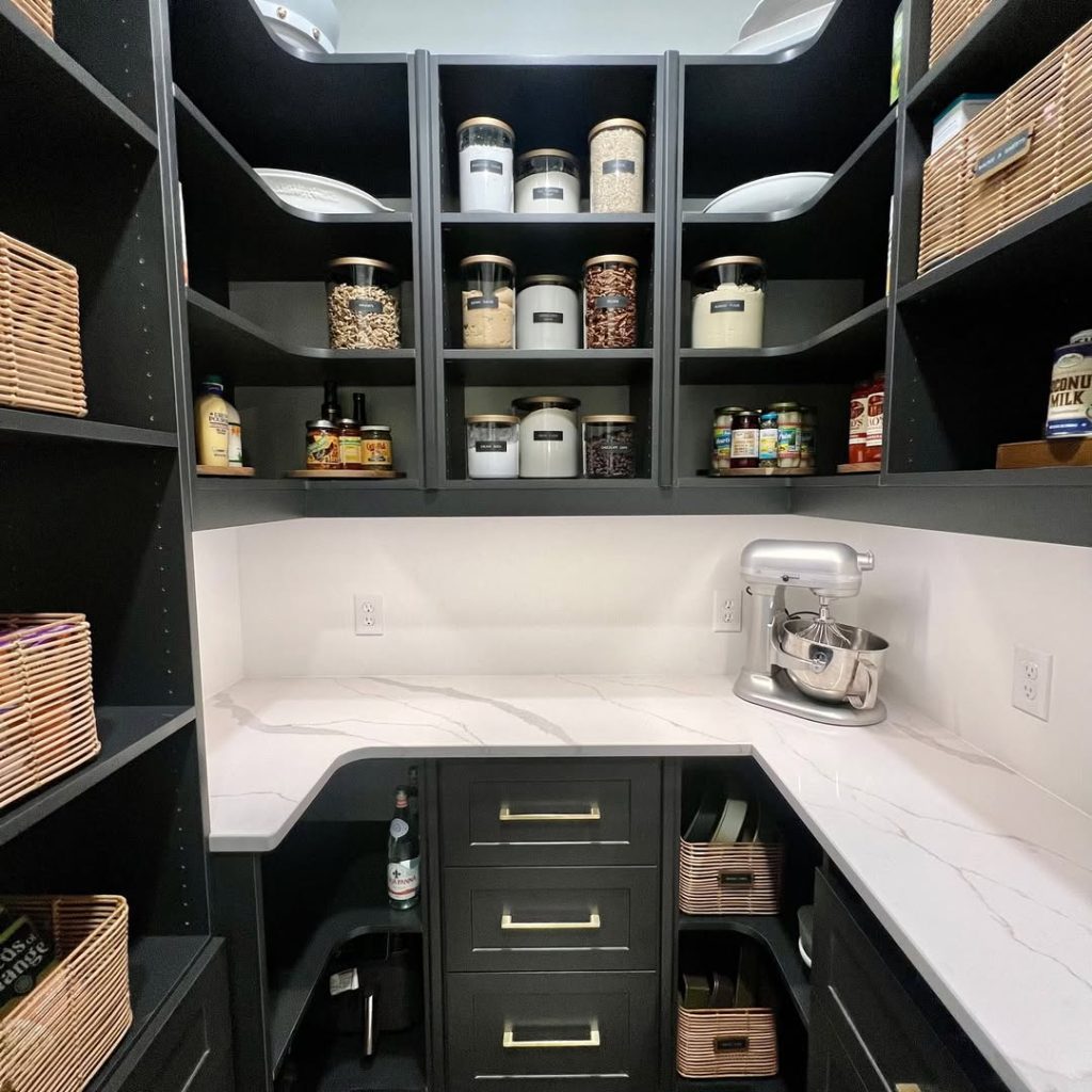 Modern black pantry with elegant storage solutions and a marble countertop.
