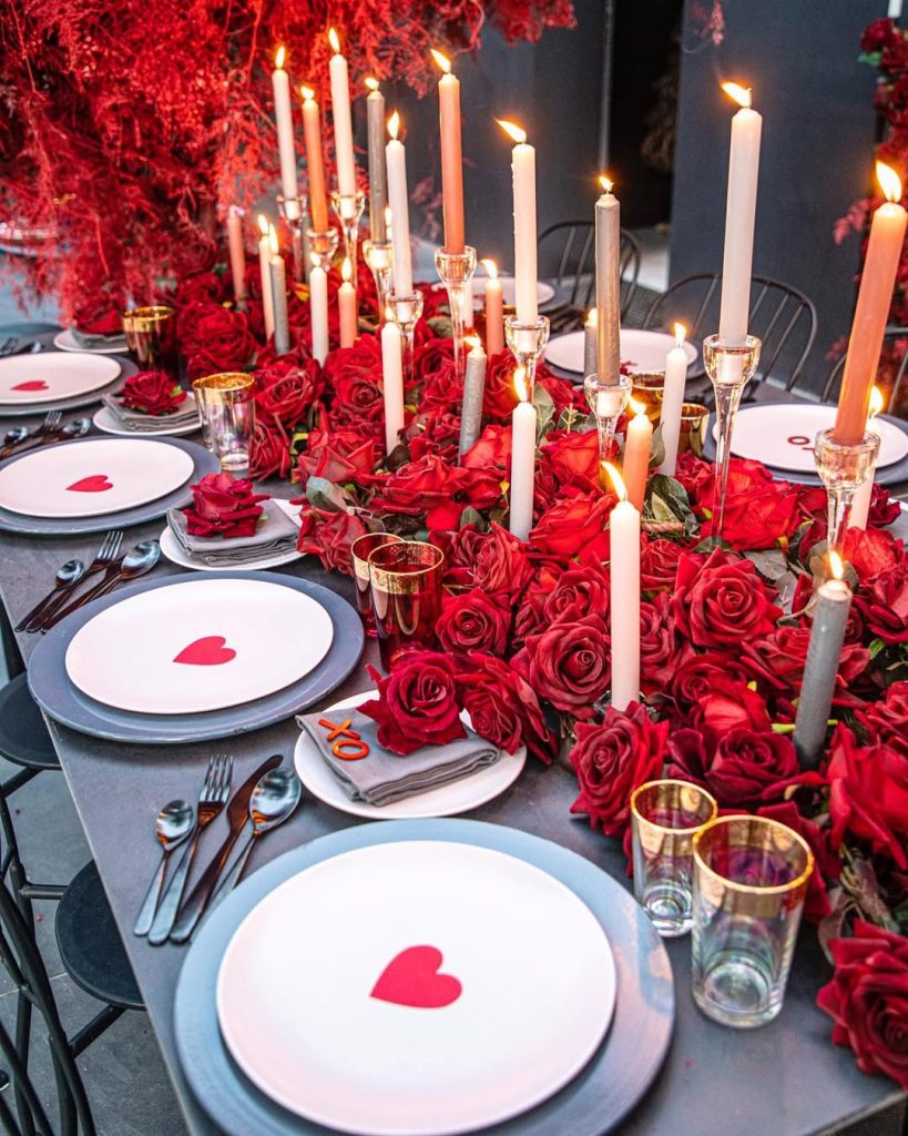 Luxurious romantic table setting for two with red roses and candlelight.
