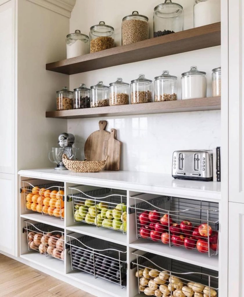 Farmhouse-style pantry with glass storage jars and fresh produce baskets.
