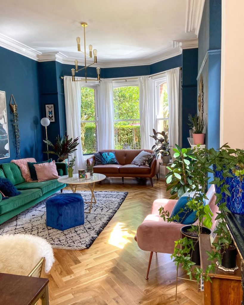 Eclectic living room with bold navy walls and colorful furniture for a vibrant vibe.