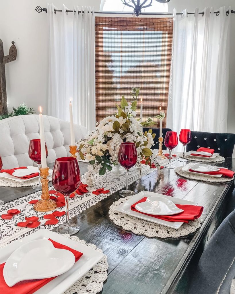 Cozy romantic table decoration with red wine glasses and floral centerpiece.
