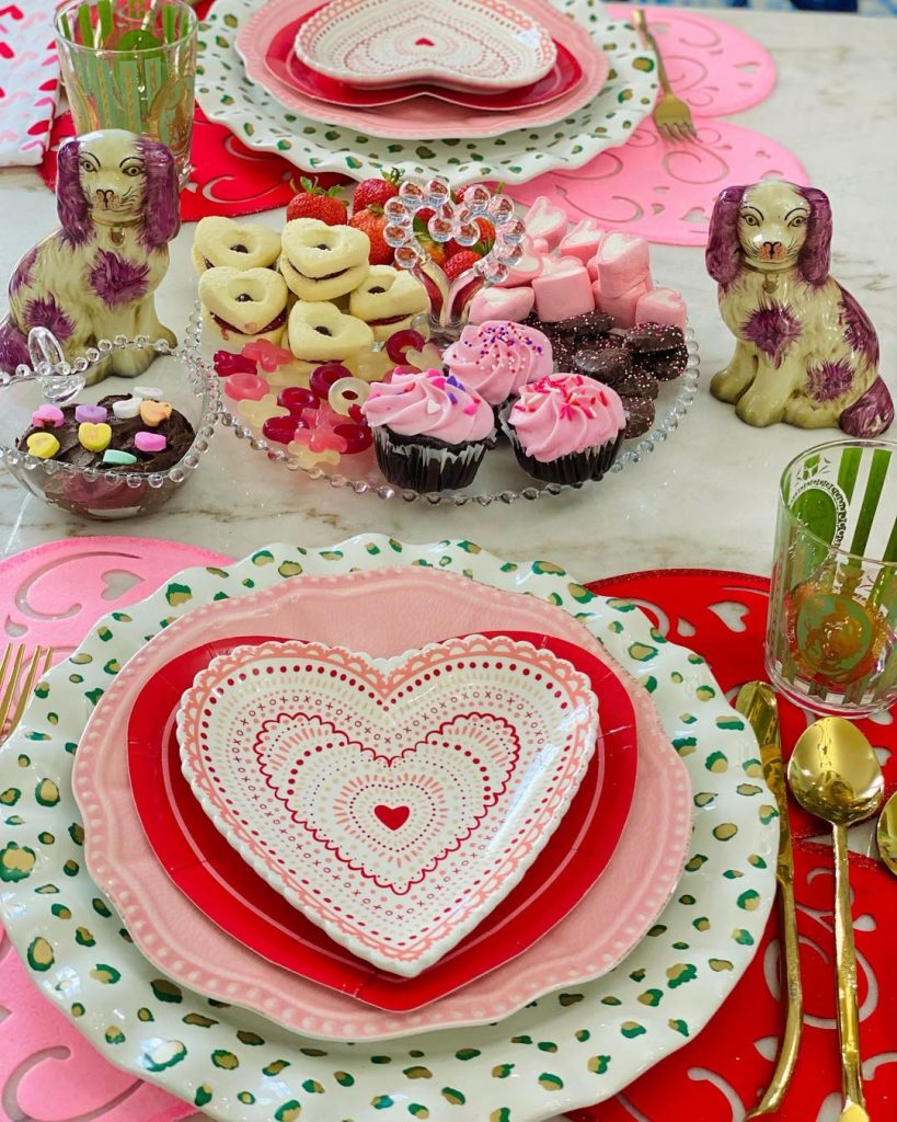 Vibrant romantic table with heart-shaped plates and whimsical dessert display.
