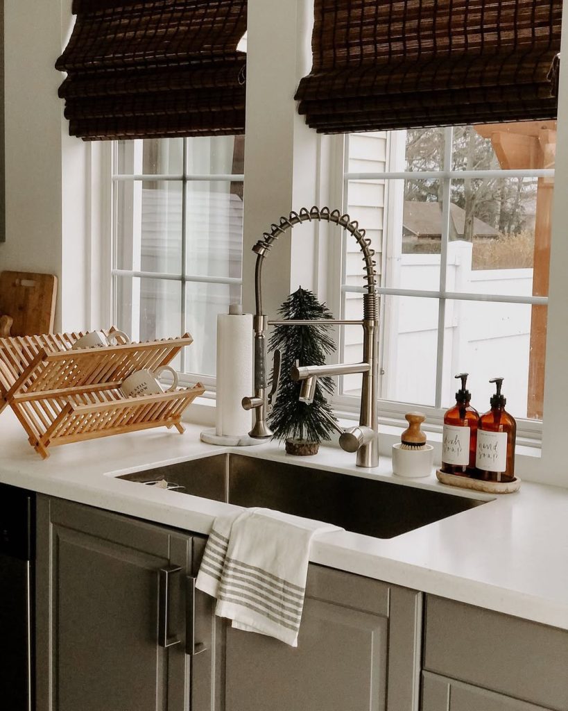 Minimalist boho kitchen with sleek black sink and bamboo blinds.
