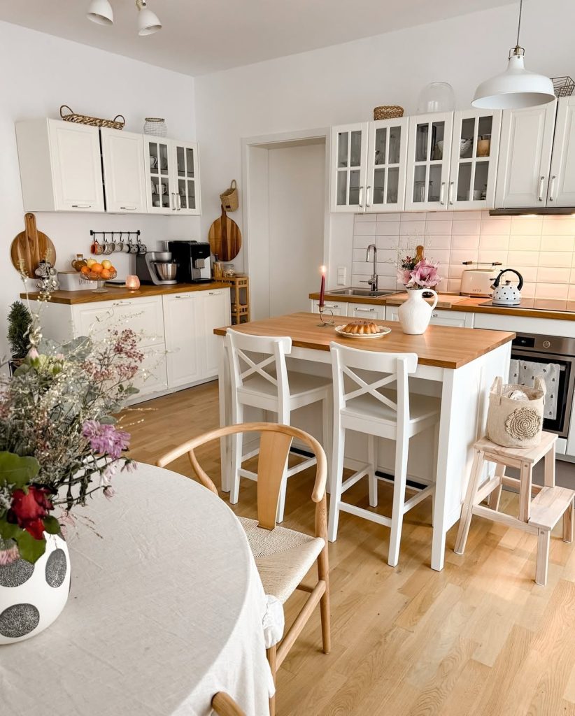 Cottage-style cozy kitchen with white cabinets, wooden countertops, and candlelight.
