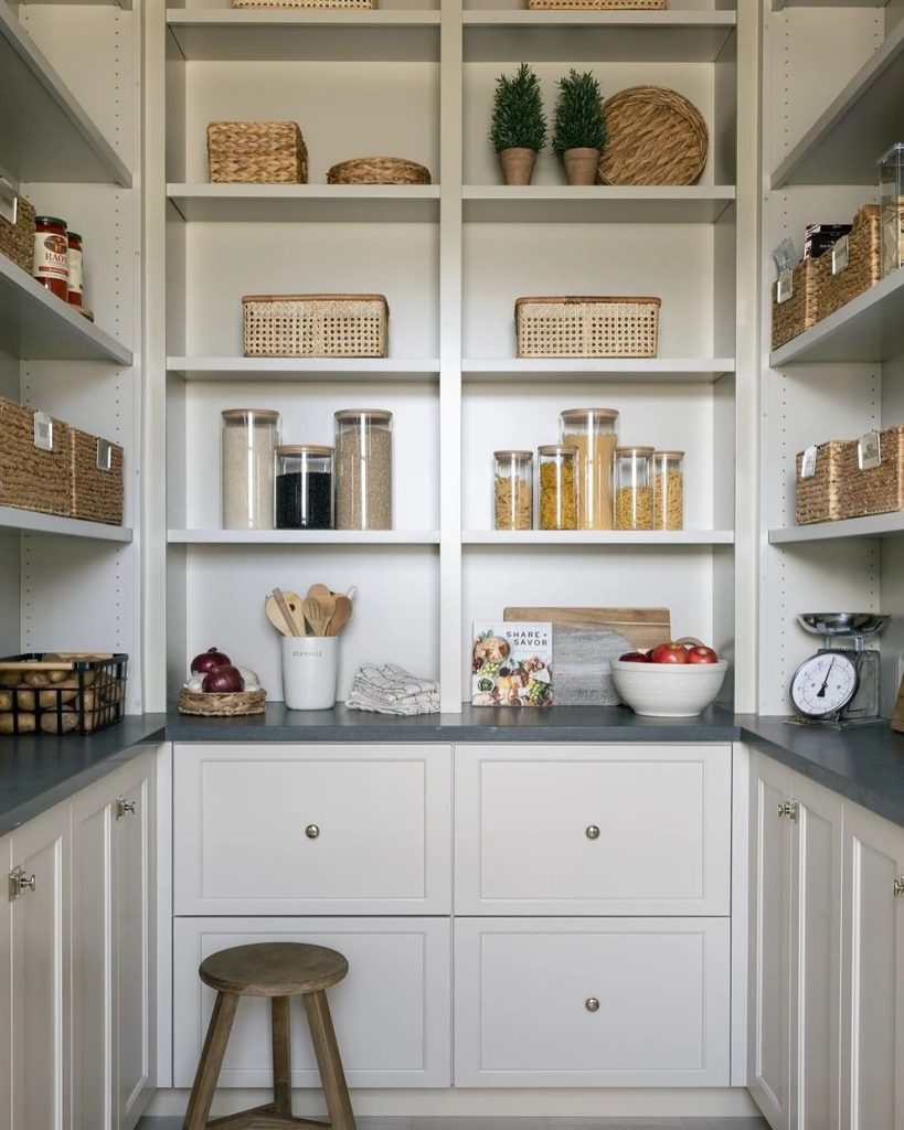 Elegant white pantry with woven baskets and neatly arranged dry goods.
