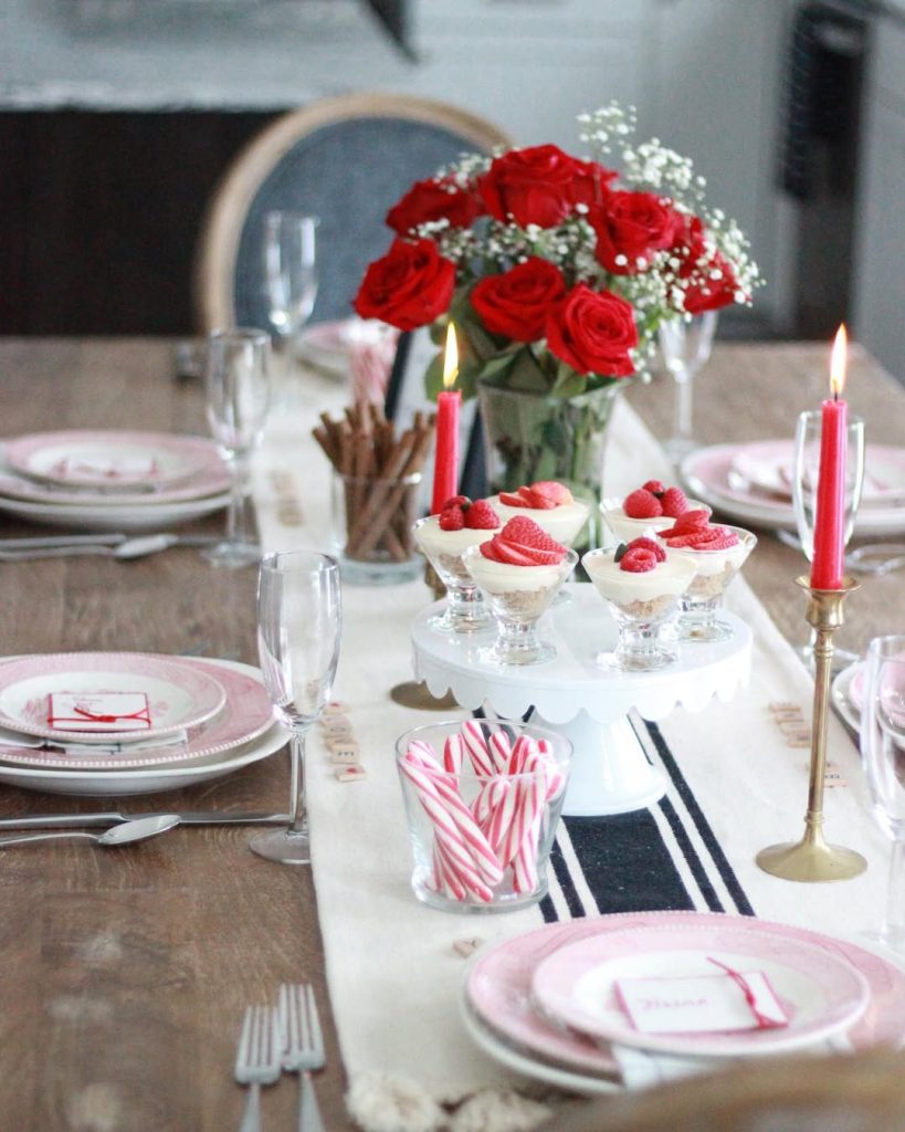 Rustic romantic table for two with red roses and soft candlelight.
