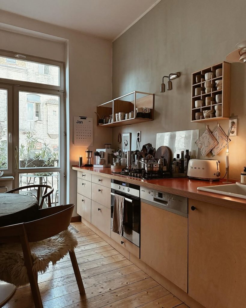 Moody cozy kitchen with warm lighting, open shelving, and vintage decor.
