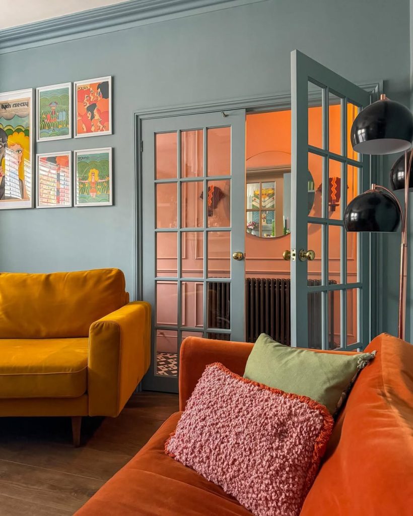 Vibrant orange and mustard sofas pop against soft blue walls in this playful living room.