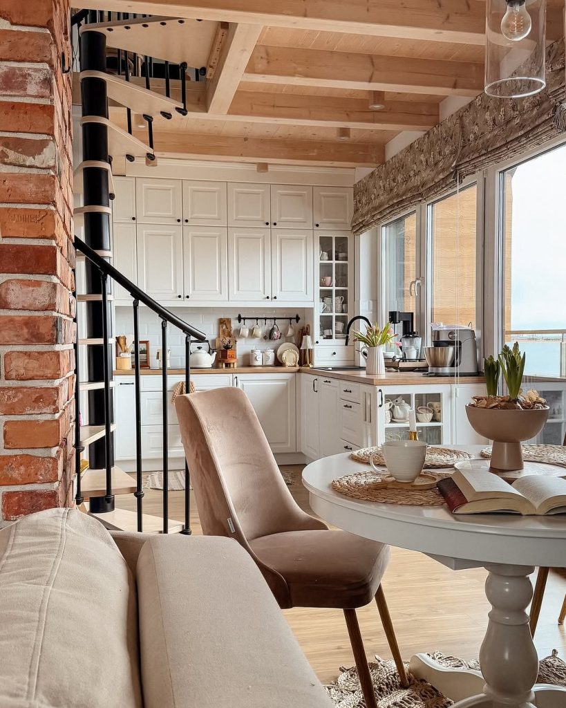 Loft-style warm cozy kitchen with exposed brick, wood beams, and a spiral staircase.
