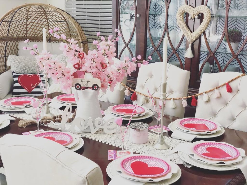 Whimsical romantic table decoration with pink blossoms and heart accents.
