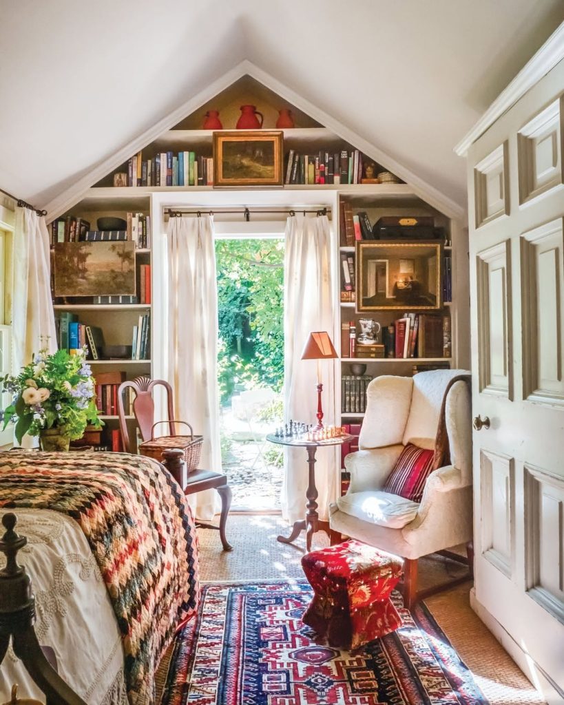 A cozy bedroom featuring a neatly made bed, filled bookshelves, and a soft rug on the floor.