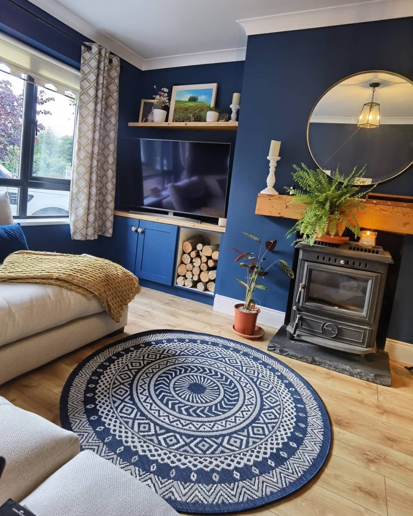 Patterned wallpaper and cozy blue sofa bring a charming and timeless vibe