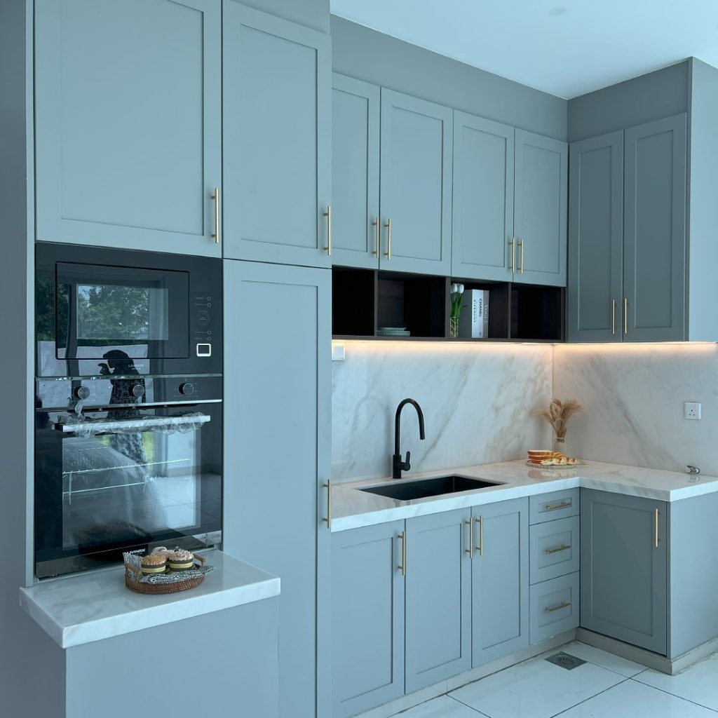 Cool-toned blue-gray kitchen cabinet ideas with gold accents and marble countertops
