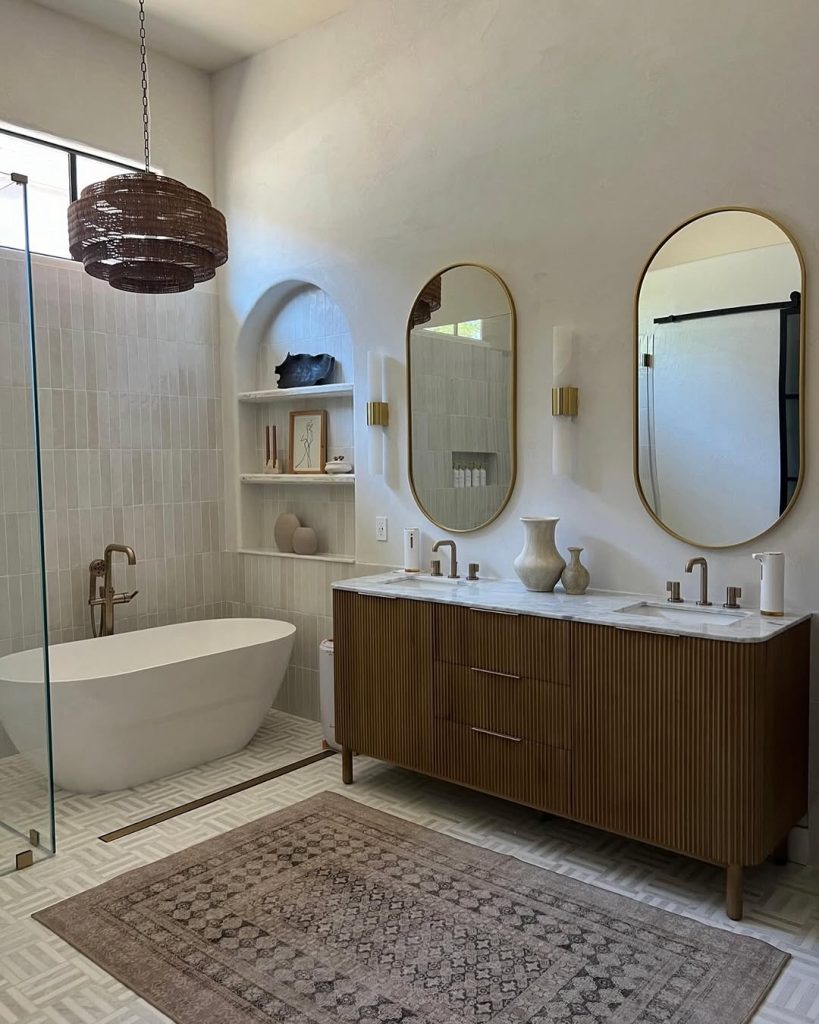 Boho-chic bathroom with two separate vanities, fluted wood, and gold accents.
