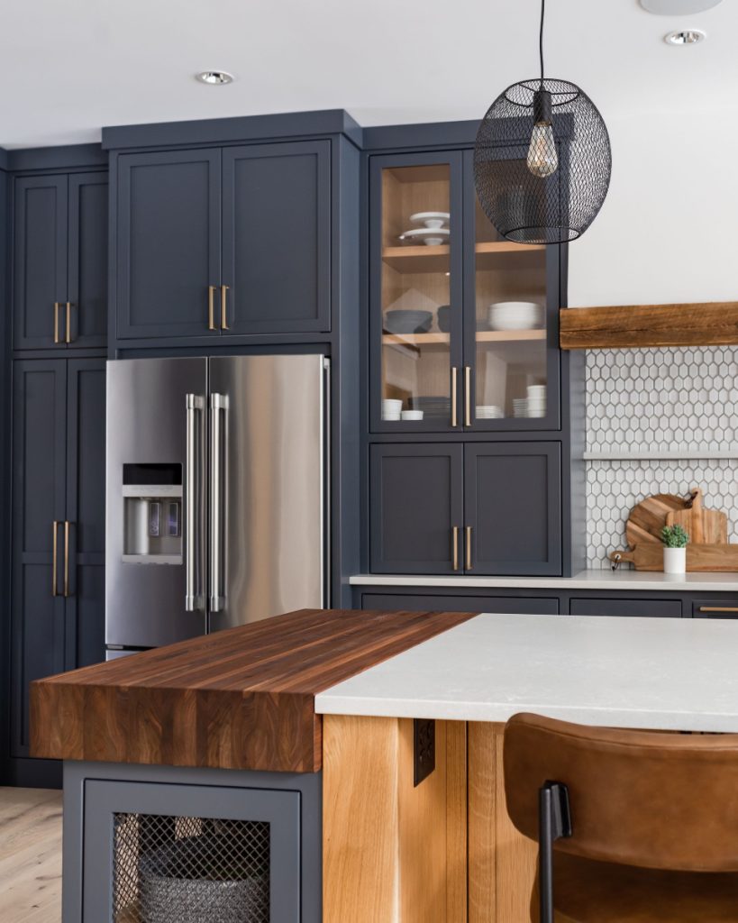 Bold navy kitchen cabinets with glass doors and gold hardware for storage
