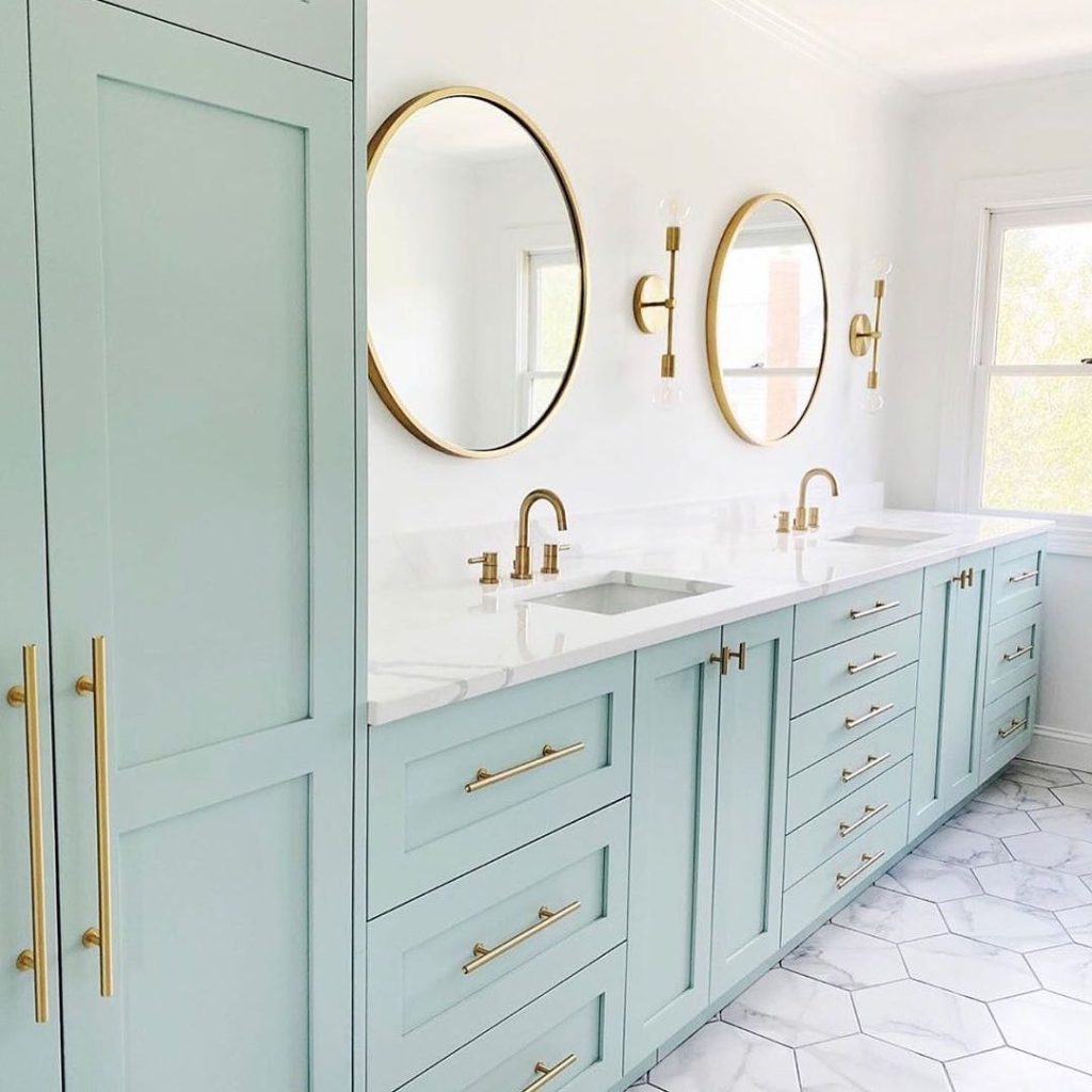 Bright and airy coastal-inspired double vanity with blue cabinetry and gold hardware.
