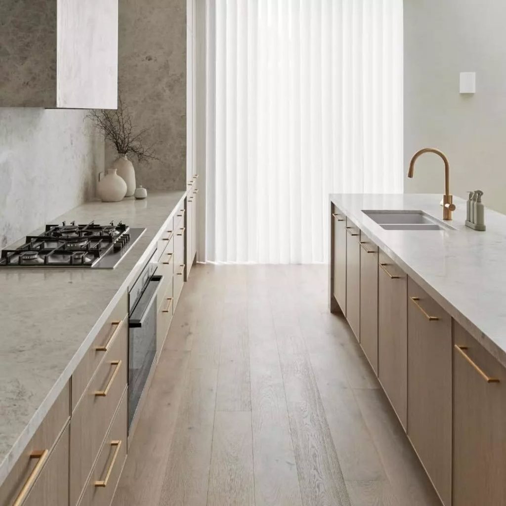 Minimalist kitchen with soft wood cabinets, gold hardware, and extra storage
