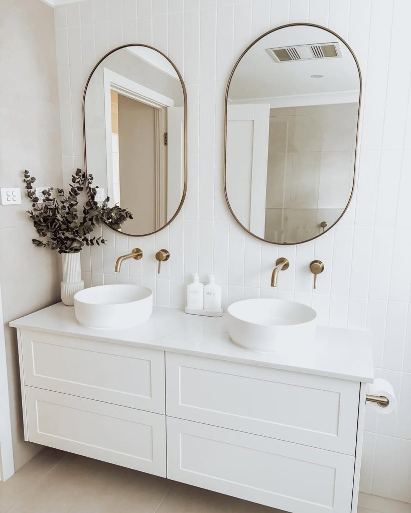 Warm wood double vanity with gold accents and oversized mirrors.
