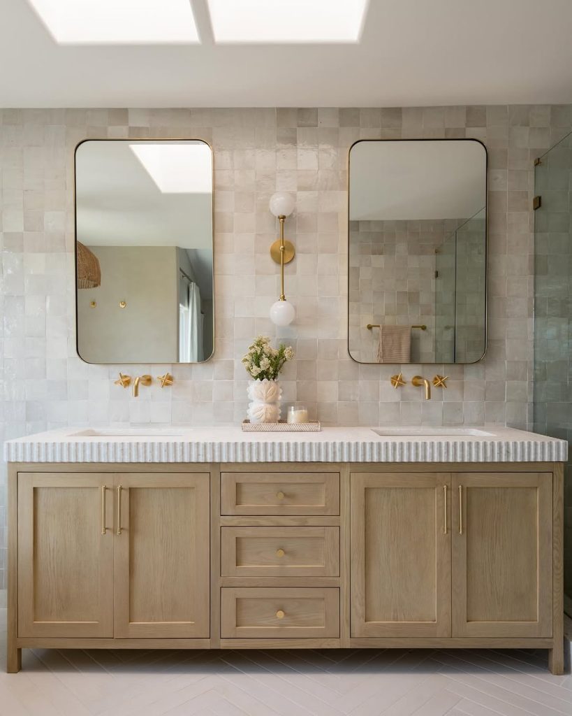 Elegant bathroom with two separate vanities and brass wall-mounted faucets.
