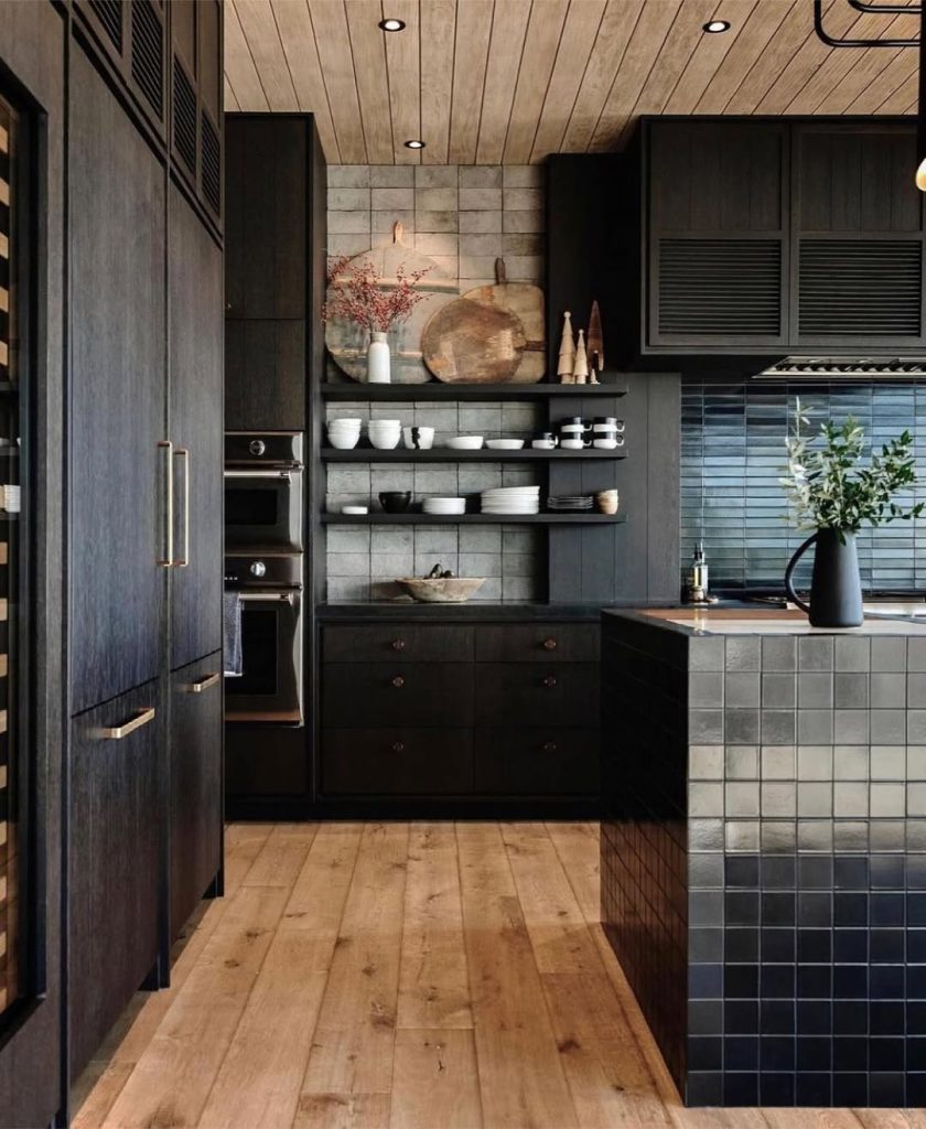 Moody black kitchen cabinets with warm wood tones and stylish pantry shelving
