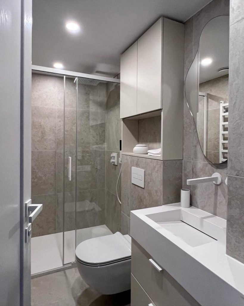 Sleek modern small bathroom with beige marble and elegant lighting.
