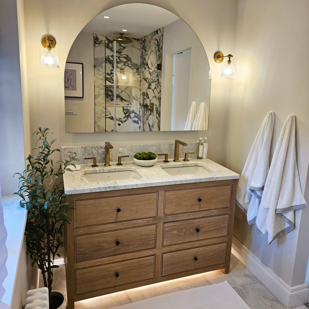 Sophisticated modern double vanity bathroom with neutral tones and brass sconces.
