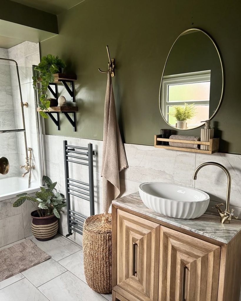 Earthy green small bathroom with wooden vanity and natural decor.
