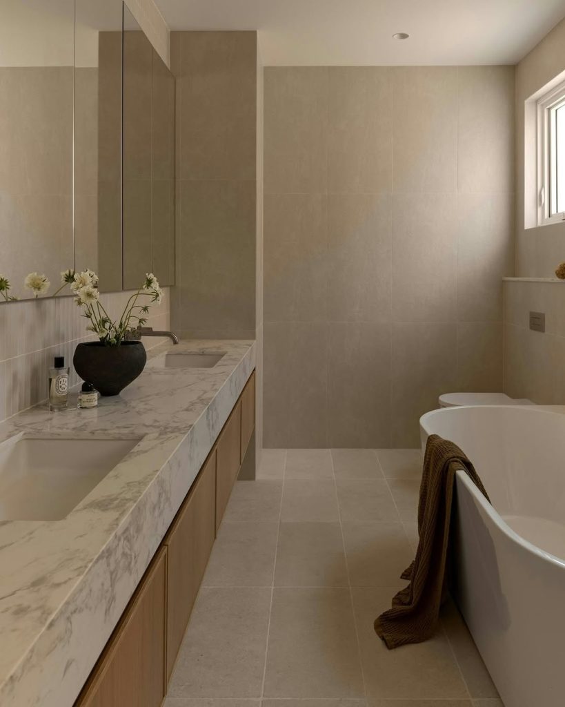 Minimalist modern double vanity bathroom with neutral tones and marble countertop.
