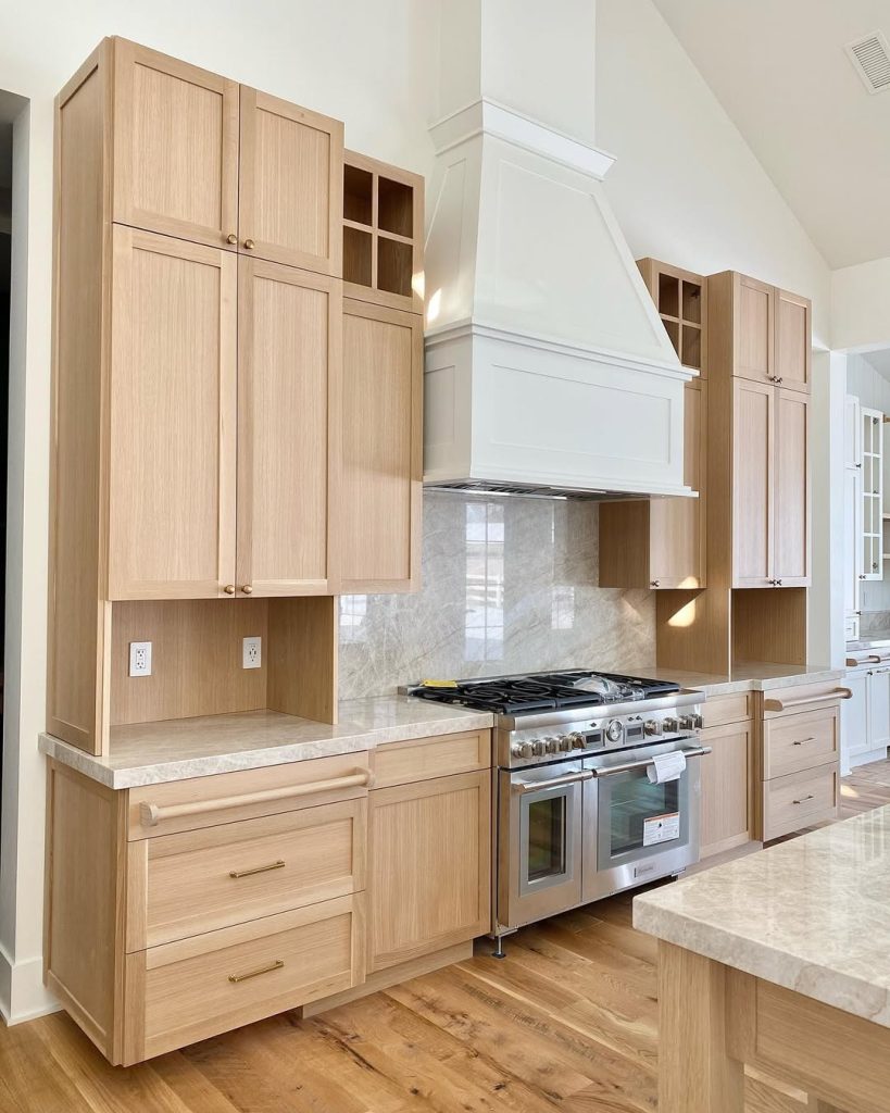 Light oak kitchen cabinets with marble countertops and smart storage solutions
